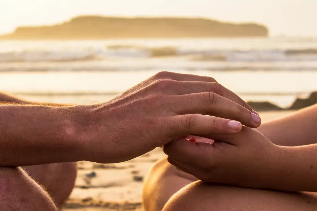 Couple meditating together on the beach to practice mindful sex